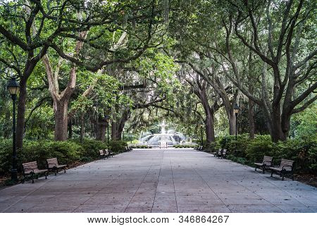 Forsyth Park Fountain With Large Trees And Park Benches In Savannah, Georgia, United States