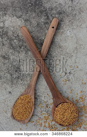 Fenugreek Seeds In Wooden Spoon On Textured Background