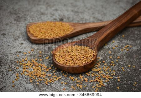 Fenugreek Seeds In Wooden Spoon On Textured Background