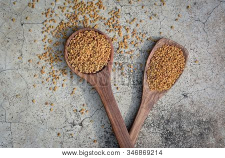 Fenugreek Seeds In Wooden Spoon On Textured Background
