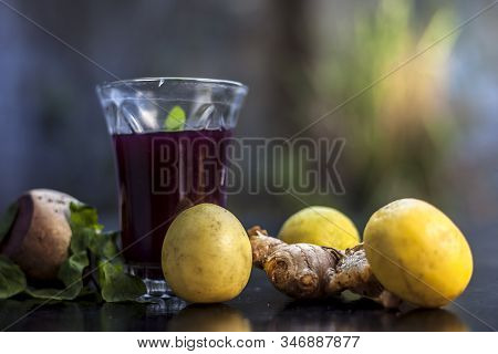 Beetroot Juice With Some Mint Leaves Lemon Juice And Ginger In It On Black Glossy Surface In A Glass