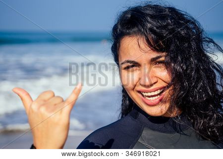 Indian Woman With Snow-white Smile Girl In Wetsuit Showing Gesture Mahalo Shaka Hand Sign Signal Say