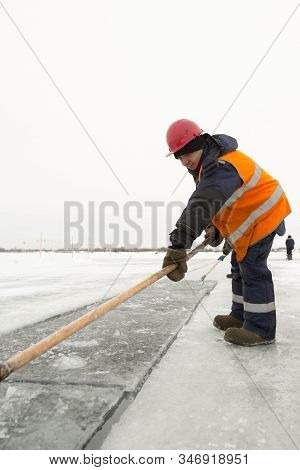 Worker Rafts Ice Blocks Along A Canal Carved In A Frozen Lake