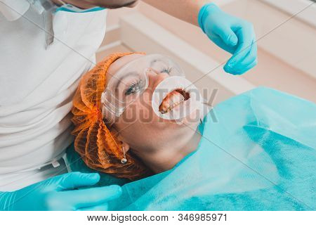 A Young Female Dentist Pulls A Mouth Extender At A Dental Clinic.