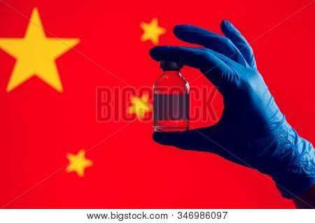 A Doctor In Blue Medical Gloves Holding An Ampula With Vaccine In Front Of Flag Of China. Close Up S
