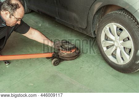 Mechanic Putting A Jack Under A Car To Lift It Into A Garage