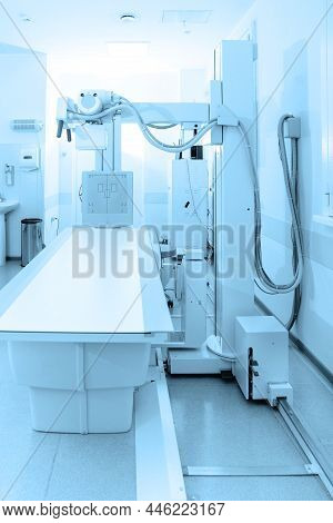 X-ray Department In Modern Hospital. Radiology Room With Scan Machine With Empty Bed. Technician Adj