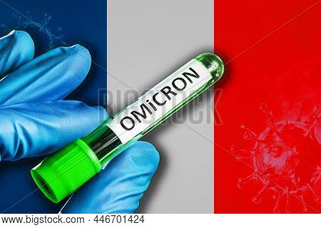 France Outbreak Of Omicron Variant. Hand Holds A Test Tube With Covid-19 Virus Omicron In Front Of F