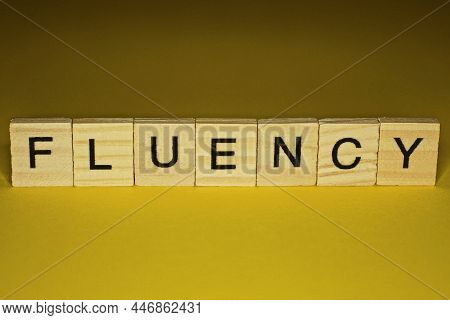 Word Fluency Made From Wooden Letters Lies On A Yellow Table