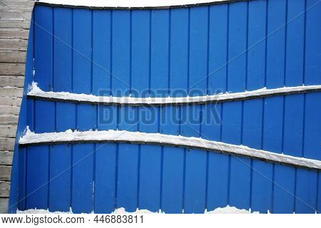 Wavy-shaped Benches Made Of Blue Wood Are Covered With Snow