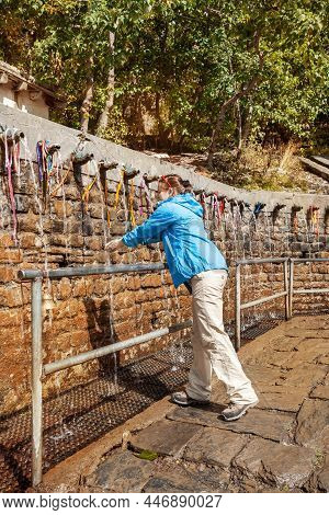 108 Holy Springs At Muktinath. Young Woman Washes Her Face And Hands In Holy Springs. Sacred Place O