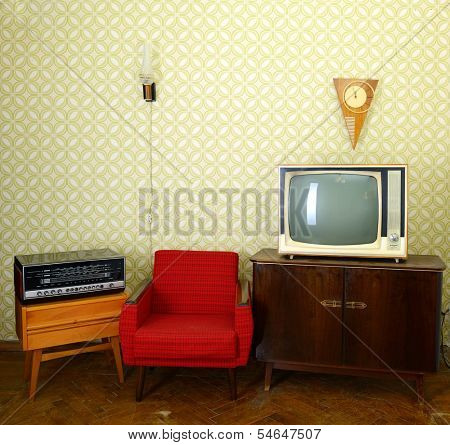 Vintage room with wallpaper, old fashioned armchair, retro tv, clocks, radio player and lamp