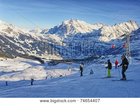 Men And Women On Ski  And Snowboards Near Cable Railway On Winter Sport Resort In Swiss Alps