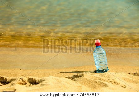Bevarage. Bottle Of Water Drink On A Sandy Beach.