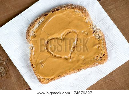 Tosted Peanut Butter Sandwich On Tissue Against Wooden Board With Heart Shape