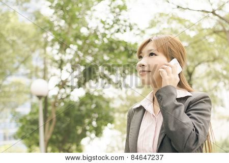 Asian young business woman use cellphone at the street, shot at Xinyi business district, Taipei, Taiwan.