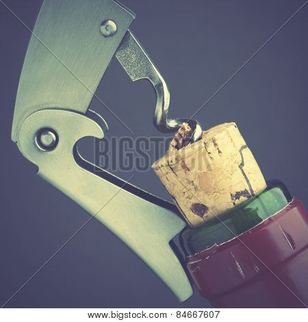 Opening of wine bottle by corckscrew. Retro style filtred image