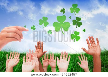 Hands raising in the air against field of grass under blue sky