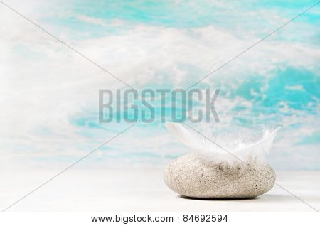 White feather on a stone: background for a condolence or spa concept.