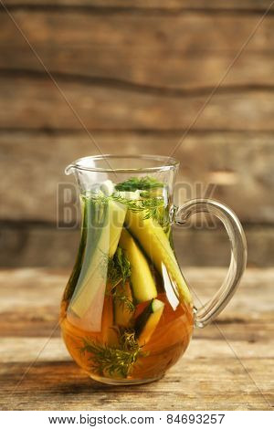 Glass ewer with fresh organic cucumber water on wooden table