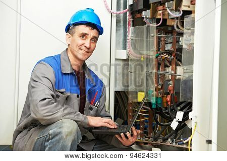 electrician engineer inspector with computer near the fuse box