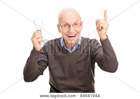 Joyful senior holding a light bulb and gesturing with his hand as if he is having an idea isolated on white background