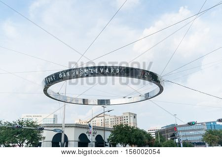 Houston, USA - August 14, 2016: Houston, Uptown District Post Oak Boulevard unique circular stanless steel reflecting street direction sign held by wires across the intersection with car reflections in shiny surface