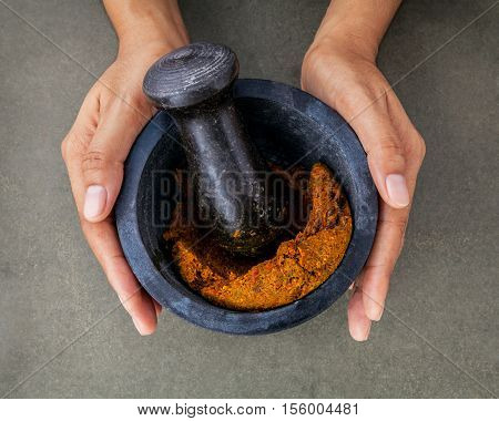 The Women Hold Stone Mortar With Spice Paste And Pestle. Thai Red Paste Ingredients For Red Curry On