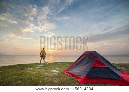 Camping day. Alone tourist stands near tent and enjoy beautiful view beautiful sunrise
