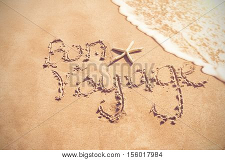Bon voyage written on sand at beach