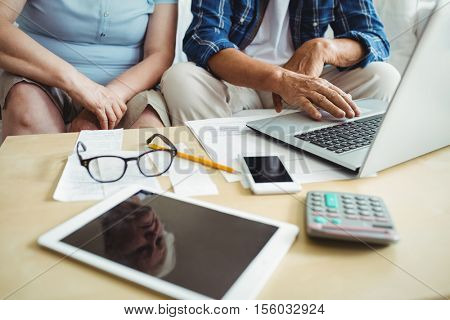 Mid-section of senior couple using laptop Mid-section of senior couple using laptop at home