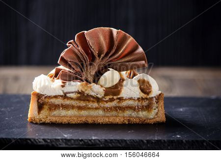 Tartlets with custard, caramel and almound served on dark table