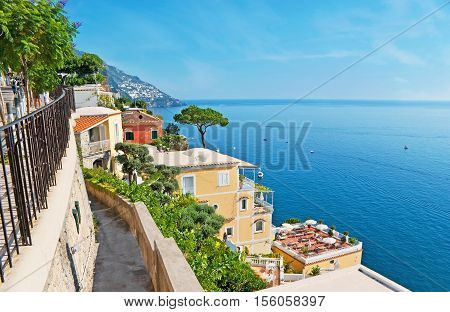 The narrow descent leads to mediterranean villas with cozy terraces on roofs lush gardens luxury hotels family restaurants and winehouses of Positano resort Italy.