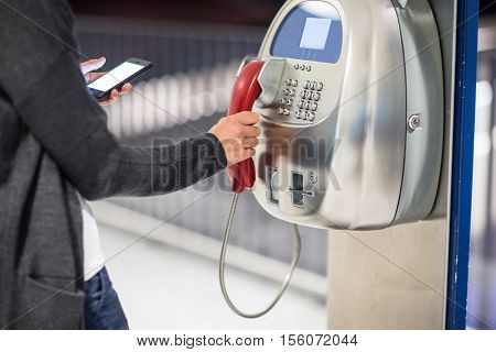 Beautiful young woman using a public phone in an airport