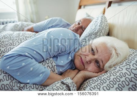 Senior man sleeping while woman still awake on bed in bed room