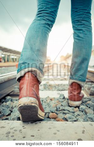 Young hipter walk in railway at train station with a traveler. travel concept. Vintage filter effect.