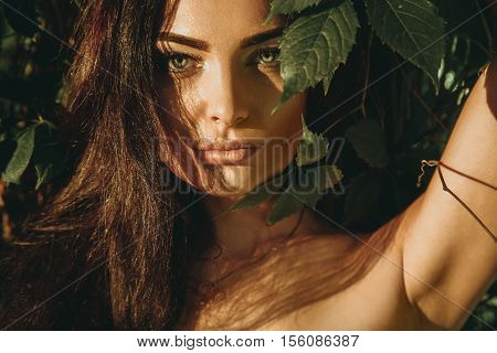 Closeup portrait of sensual young girl outdoors in the forest looking at the camera