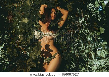 young beautiful girl in underwear leaf posing outdoors in the forest