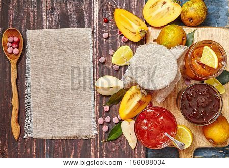 berry and fruit jam with ingredients and linin napkin on a dark rustic background. Copy space top view.