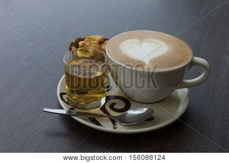 hot fresh coffee in white glass hot tea and alphabet biscuit with tree shape of heart foam on wooden table city view at sunset at coffee time / hot fresh coffee and tea