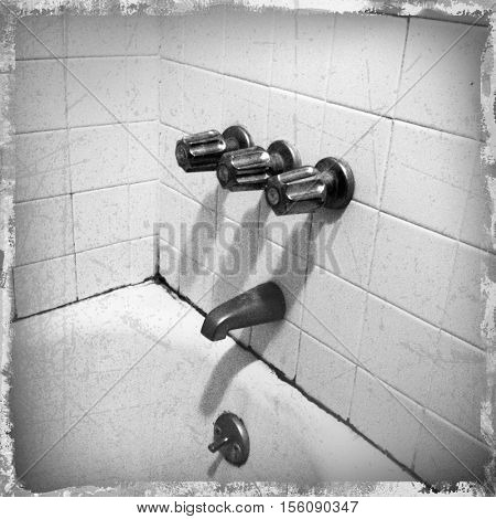 filtered black and white image of an old grungy moldy bathtub in a seedy snapshot style 