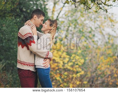 Young attractive couple in knitted sweaters having fun at sea shore