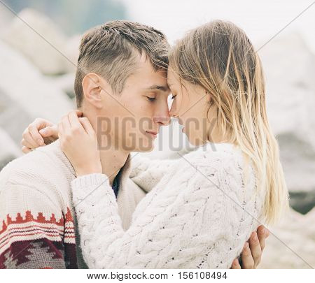 Young attractive couple in knitted sweaters hugs each other with tenderness