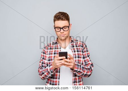 Young Handsome Man In Glasses Typing Sms On Gray Background