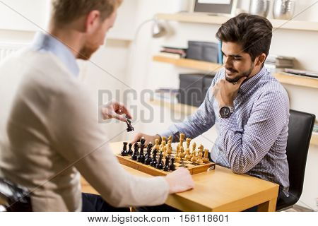 Two young men playing chess in room