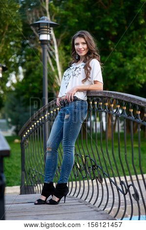 young woman standing on the bridge in jeans and a white t-shirt.