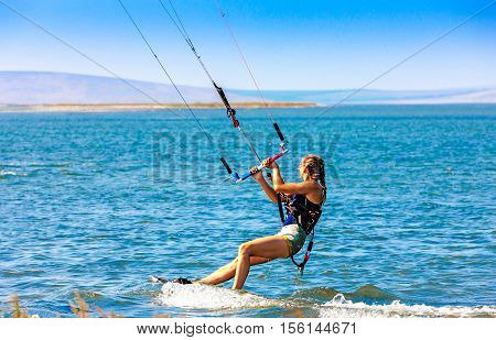 Young woman kitesurfer glides on water surface