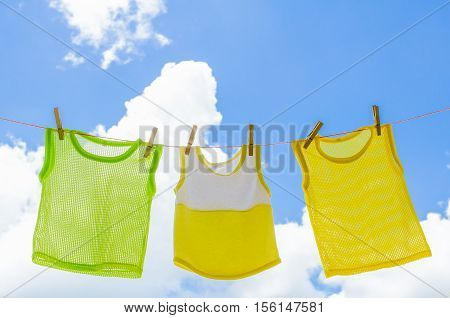 Baby clothes laundry hanging on the clotheline for sun dry after wash over blue sky in sunny day
