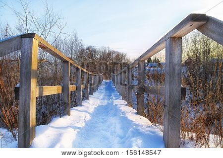 pedestrian bridge in the village covered with snow