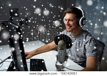 technology, gaming, entertainment, let's play and people concept - happy young man in headset with pc computer playing game at home and streaming playthrough or walkthrough video over snow